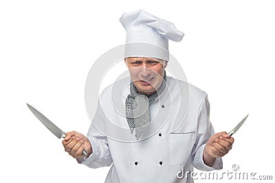 Dissatisfied cook, holds 2 knives in his hands Stock Photo