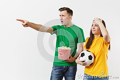 Dissatisfied couple, woman, man, football fans in yellow green t-shirt cheer up support team with soccer ball bucket of Stock Photo
