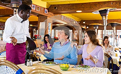 Dissatisfied guests conflicting with african american waiter in restaurant Stock Photo
