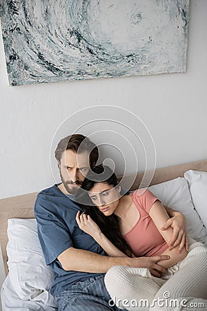 Dissatisfied man in pajama hugging asexual Stock Photo