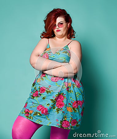 Not happy plus-size overweight lady in sunglasses and sundress with her arms crossed waits for something Stock Photo