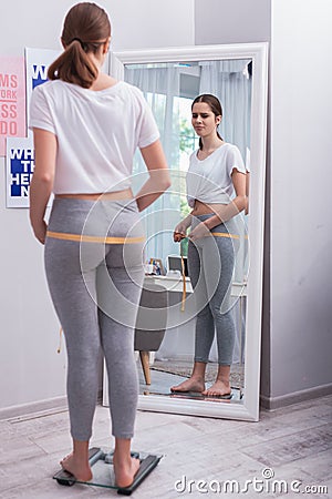 Dissatisfied teen girl starting measuring Stock Photo