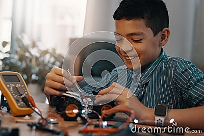 Dissembling your toys apart is way more fun anyways. a handsome young boy building a robotic toy car at home. Stock Photo