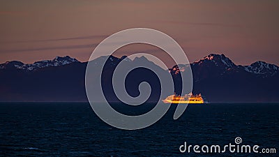 Distant cruise ship illuminated by setting sun off Alaska coast Stock Photo