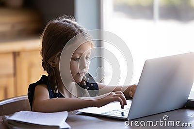 Concentrated little girl studying online doing homework on laptop Stock Photo