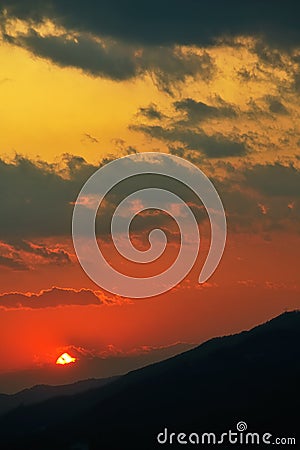 Distant sunset over silhouettes of crests of hills Stock Photo