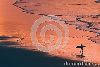 Distant surfer silhouette in the shore at sunset Stock Photo