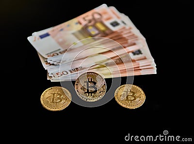 Distant view of a group of Euro banknotes, next to three Bitcoin coins. on a black background. Concept of economy, money, power, Stock Photo