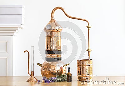 Distilling apparatus alembic with esential oil flowers at the wooden table Stock Photo