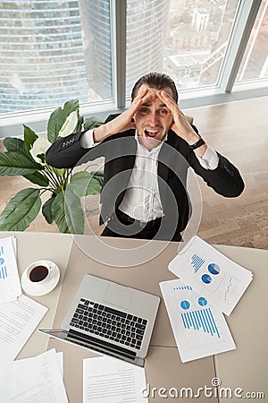 Distraught businessman at work looking up screaming in anger. Stock Photo