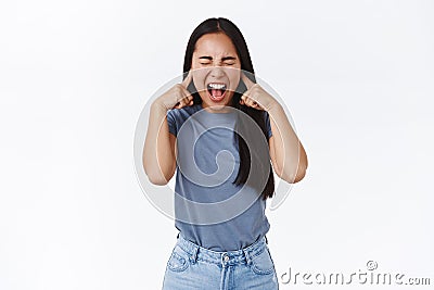 Distressed and fed up asian teenage girl with long dark hair, screaming losing temper, cant control emotions, close eyes Stock Photo