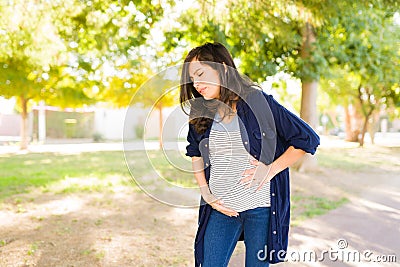 Distressed woman having contractions outdoors Stock Photo