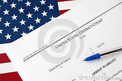 District Court Arrest Warrant court papers and blue pen on United States flag. Permission to arrest a suspect Stock Photo