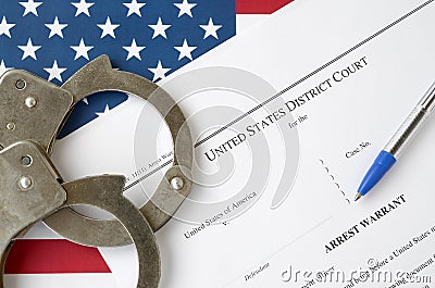 District Court Arrest Warrant court papers with handcuffs and blue pen on United States flag. Concept of permission to arrest Stock Photo