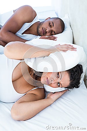 Disturbed wife sleeping besides snoring husband Stock Photo