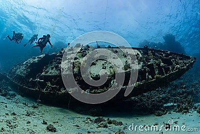 divers visiting an underwater wreck of a metal sailboat Stock Photo