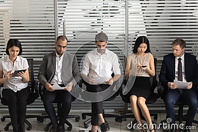 Diverse applicants sit on chairs in row in waiting room Stock Photo