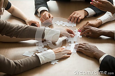 Diverse business people helping in assembling puzzle, teamwork s Stock Photo