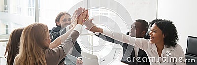 Diverse businesspeople sitting at desk celebrating success giving high five Stock Photo