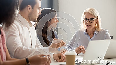 Diverse employees listening to serious mature team leader at meeting Stock Photo