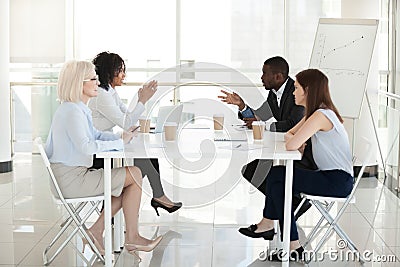 Diverse employees sit at table, discussing project in boardroom Stock Photo