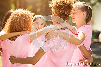 Diverse Girls In Breast Cancer T-Shirts Embracing Standing In Park Stock Photo