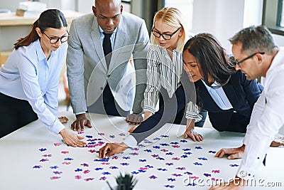 Diverse group of businesspeople working together to solve a puzz Stock Photo