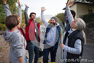 Diverse group of happy community service volunteers raising hands together outdoors in street Stock Photo