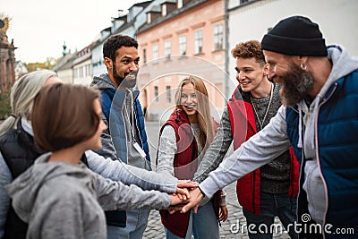 Diverse group of happy community service volunteers stacking hands together outdoors in street Stock Photo