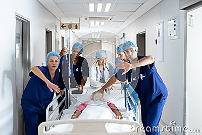 Diverse group of healthcare workers clearing the way for patient in bed in hospital corridor Stock Photo