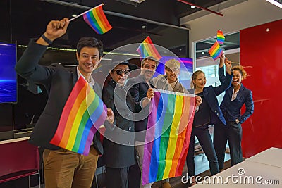 Diverse group of lgbtq people with rainbow flag on hand team up together Stock Photo