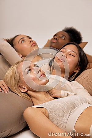 Group of four diverse ladies lying on floor in studio, calm and pacified, isolated Stock Photo