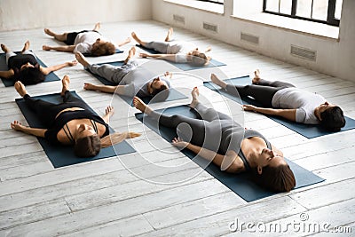 Diverse sporty people practicing yoga, relaxing in Savasana exercise Stock Photo