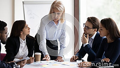 Diverse staff listening serious mature coach provide information during workshop Stock Photo