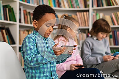 Diverse students in school, engrossed in mobile games sitting in classroom Stock Photo