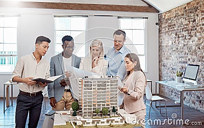 A diverse team of architects working on a building model together inside the office. A group of engineers planning a Stock Photo