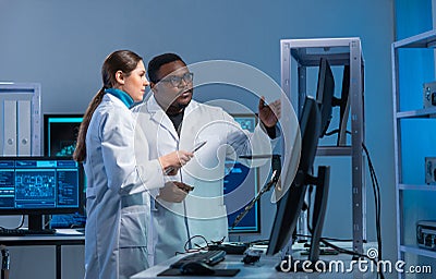 Diverse team of microelectronic engineers discuss current developments in a science lab. Workplace of microprocessor Stock Photo