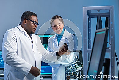 Diverse team of microelectronic engineers discuss current developments in a science lab. Workplace of microprocessor Stock Photo