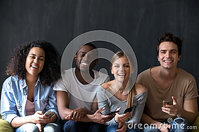 Diverse young people sitting holding phones looking at camera Stock Photo