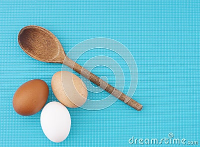 A diversity of eggs. Three chicken, hens eggs on turquoise kitchen board. Different colors: brown white and speckled. Stock Photo