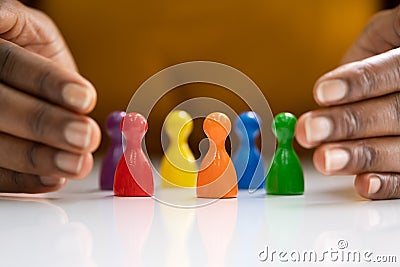 Diversity And Inclusion Concept. Hand Protecting Pawns Stock Photo