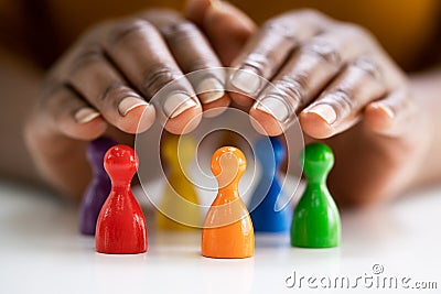 Diversity And Inclusion Concept. Hand Protecting Pawns Stock Photo