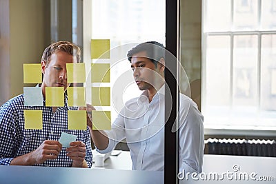 Diversity is a key ingredient to fresh ideas. two businessmen preparing for a presentation by using adhesive notes. Stock Photo
