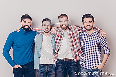 Diversity of men. Four cheerful young guys are standing and embracing, smiling, on pure background in casual outfit and jeans Stock Photo