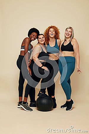 Diversity Models. Different Race And Size Women. Group Of Multicultural Friends In Sportswear With Black Fitness Ball. Stock Photo