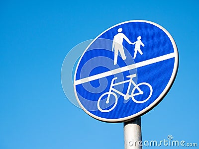 Divided path for cyclists and pedestrians blue road sign, object detail, closeup, isolated on blue sky background. Road signs Stock Photo