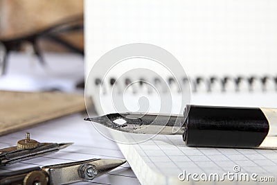 Dividers and the old penholder with the pen lies on the notebooks sewn with metal springs on a wooden table. Selective focus. Retr Stock Photo