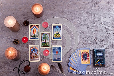 Divination cards alignment with feathers and candles on silver background. Mystery, astrology, fortune telling, belief, wisdom Editorial Stock Photo