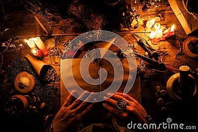 Divination with the help ancient books and of the dry African herbs. The light from the candles on the old magic table. Attributes Stock Photo