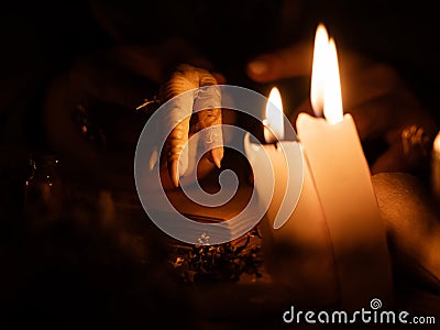 Divination with the help of chicken feet and dry herbs. The light from the candles on the old magic table. Attributes of occultism Stock Photo